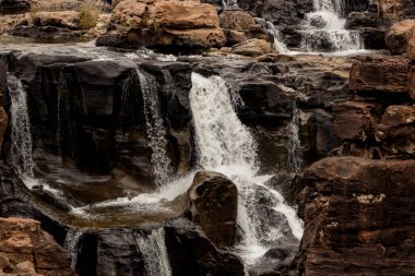 Çok sayıda şelale karanlık kayaların üzerinde akıyor.