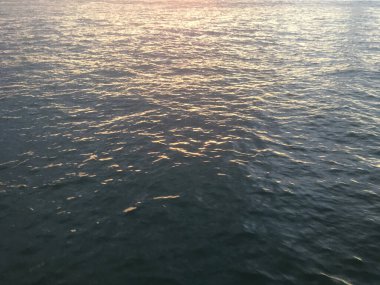 New York Limanı 'nda sakin bir su. Okyanus suyundaki günbatımının yansıması. Arkaplan deniz suyu dokusu.