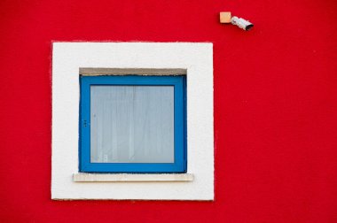 Parlak güneşin altında, renkli alçılı ve farklı renkli pencereli bir binanın renkli cephesinin bir parçası..