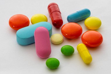 Beyaz arka planda çok renkli yuvarlak ve oval tabletler ve haplar.