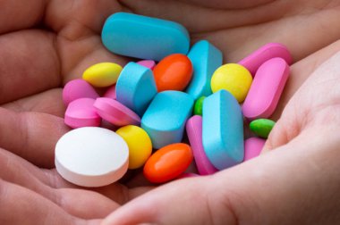 Avuç içlerine çok renkli yuvarlak ve oval tabletler.
