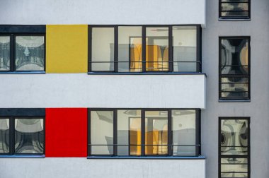 Pencerelerinde yansımalar olan çok renkli bir binanın ön cephesinin bir parçası..