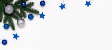 Köknar dalları, beyaz arka planda mavi ve gümüş süslemeleri olan bir Noel tablosu. Noel kompozisyonu, üst görünüm, kopyalama alanı. Yeni yıl arkaplanı.