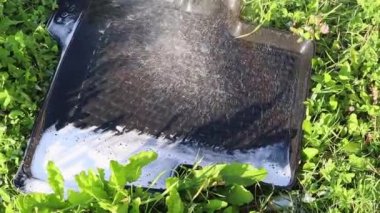 Bir su püskürtüsü araba paspasının üzerine dökülüyor, köpüğü temizliyor. Yavaş çekim