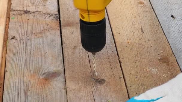 Taladro amarillo perfora un agujero en una tabla de madera. Cámara lenta, primer plano FullHD — Vídeo de stock