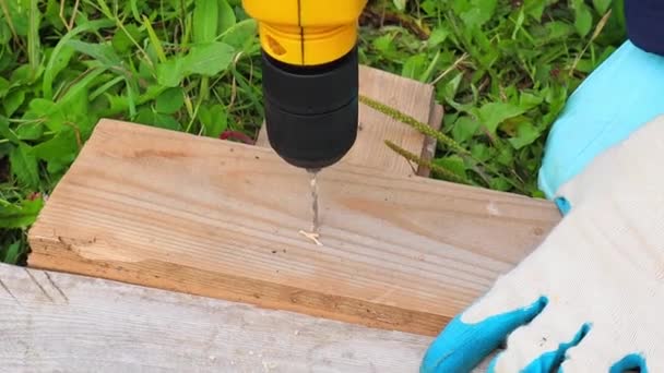 Yellow drill drills a hole in a wooden Board. Slow motion, close-up FullHD — Stock Video