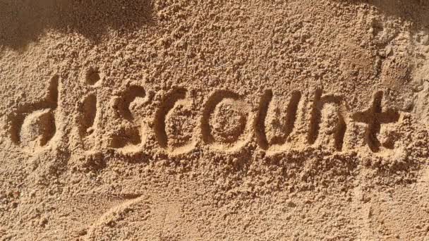 La palabra descuento escrita en un montón de arena está cubierta de arena suelta. — Vídeo de stock