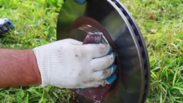 Ein behandschuhter Mechaniker schleift vorsichtig den Rost vom Bremsrotor ab. Full HD — Stockvideo