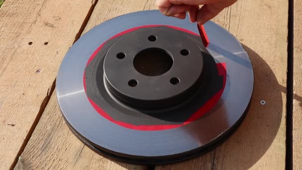 Mannelijke hand langzaam verwijdert rode duct tape van geschilderde auto remschijf. VollHD — Stockvideo
