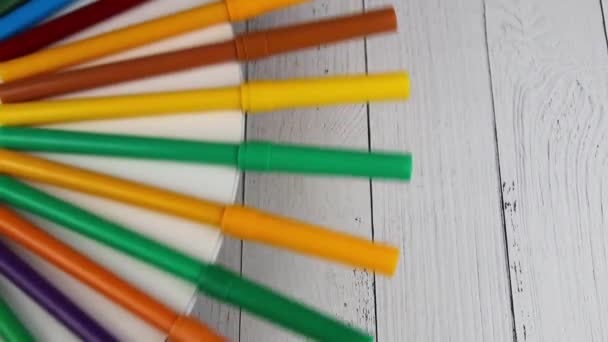 Різнокольорові ручки для фетру обертаються на круглому столі на дерев'яному фоні — стокове відео