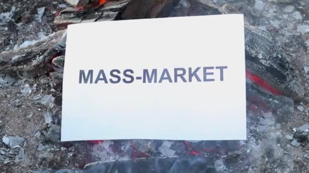 Palabra Mercado de masas en una hoja blanca de papel se quema en un fuego contra. — Vídeo de stock