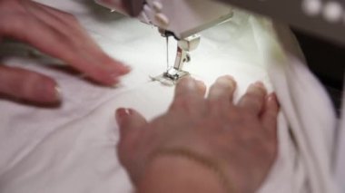 Bir terzinin elleri dikiş makinesine kumaş parçaları diker. Tam HD
