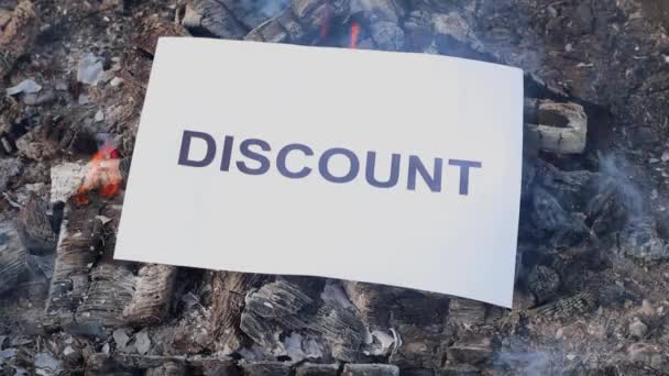 Word Discount on a white sheet of paper burns into a fire against. Slow motion — Stock Video