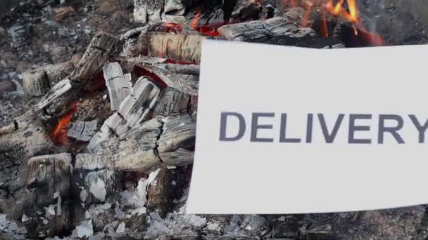 Word Delivery su un foglio bianco di carta brucia in un fuoco contro. Rallentatore — Video Stock