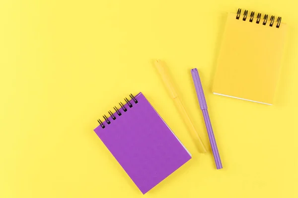 Closed notebooks with markers on yellow background flat lay. — Stock Photo, Image