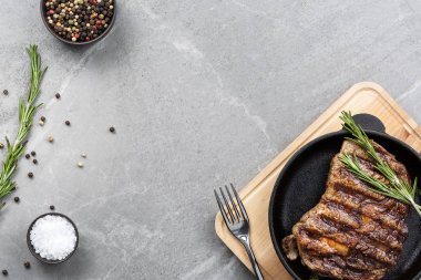 Gri mermer masa manzaralı tavada kızarmış biftek.