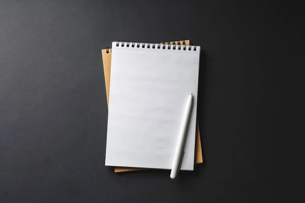 Cuaderno con pluma blanca sobre fondo negro, vista superior — Foto de Stock