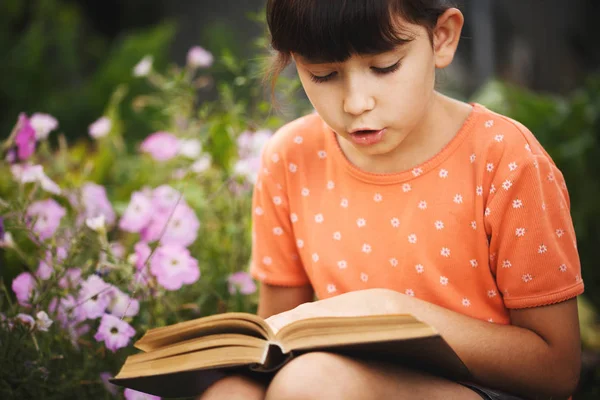 かわいい女の子は晴れた日、国際識字の日に屋外で読書しています. — ストック写真