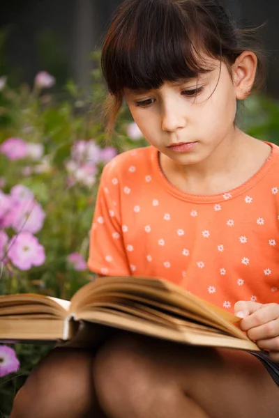 かわいい女の子は晴れた日、国際識字の日に屋外で読書しています. — ストック写真