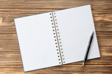 Ahşap masadaki boş çarşaflı kalem defteri.