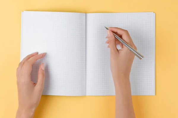 Menina escreve em um notebook aberto vista superior, fundo amarelo — Fotografia de Stock