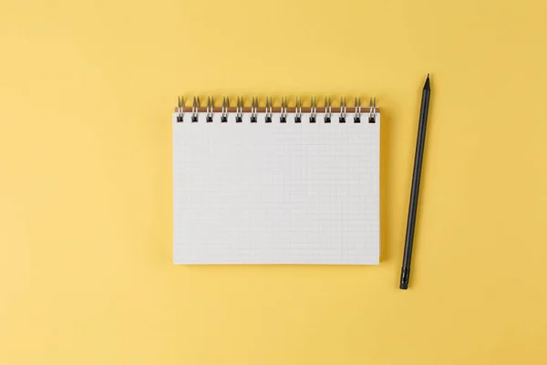 Notebook with a pencil on a yellow background top view — Stock Photo, Image