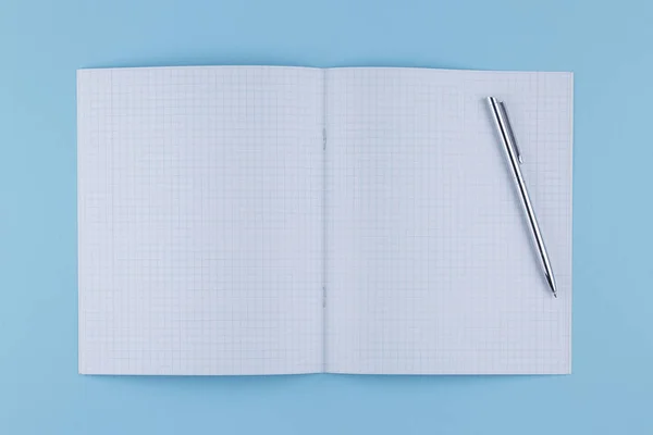 School notebook with pen on a blue table top view — Stock Photo, Image