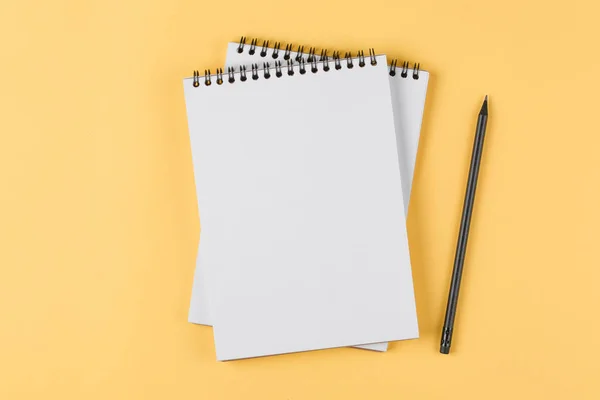 Cuaderno con lápiz negro sobre fondo amarillo vista superior — Foto de Stock