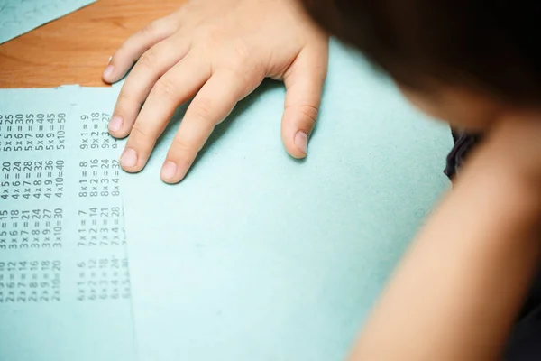 Ребенок учится таблице умножения за столом, домашнее задание — стоковое фото