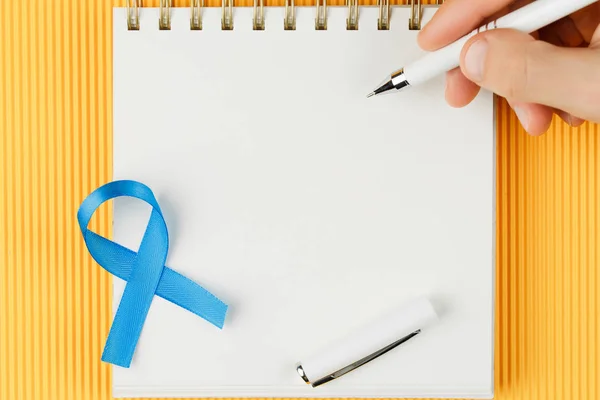 Ruban de prostate bleu sur carnet ouvert isolé sur fond jaune — Photo