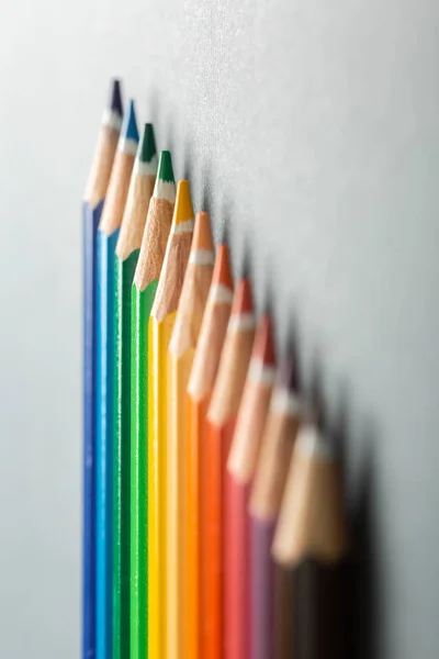 Colored pencils in row on a gray background top view. — Stock Photo, Image