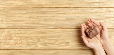 ahşap arka plan üst görünümünde ellerde hediye kutusu