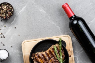 gri mermer masa üstü görünümünde şarap şişesi ile tavada kızarmış biftek