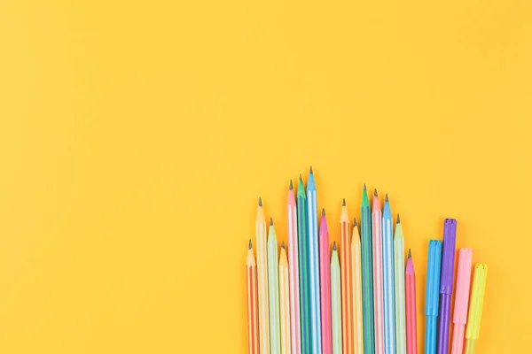 Lápis multicoloridos em um fundo isolado amarelo — Fotografia de Stock