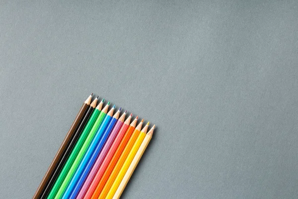 Lápices de colores en fila en una vista superior de fondo gris . — Foto de Stock