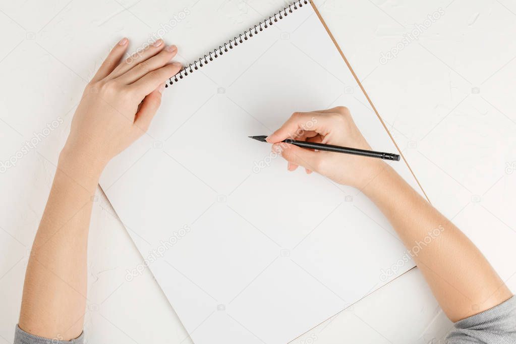 notebook with empty sheet on a white background with pencil in hands