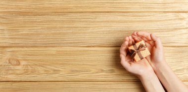 ahşap arka plan üst görünümünde ellerde hediye kutusu