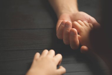 Yaşlı bir adamın genç bir adamın elini tutan eller.