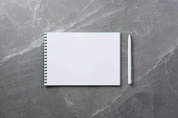 Блокнот з білою ручкою на мармуровому фоні, вид зверху — стокове фото