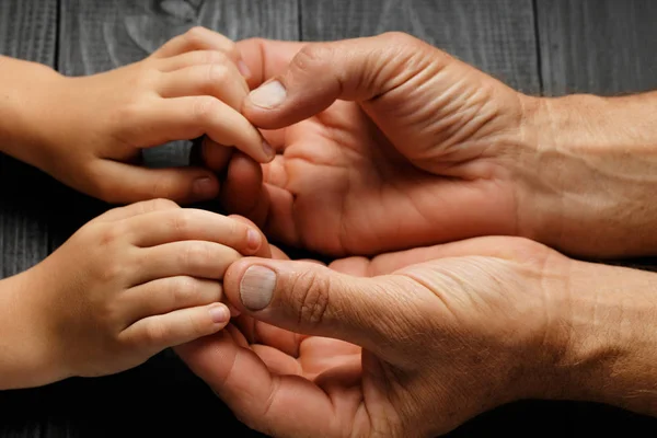 Main d'adulte tenant la main d'un enfant, concept d'aide familiale — Photo