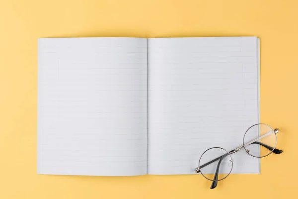 Notizbuch mit Brille auf gelbem Hintergrund von oben — Stockfoto