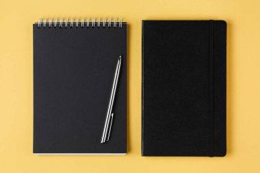sarı arka plan üst görünümünde siyah kağıt ve kalem ile dizüstü bilgisayar