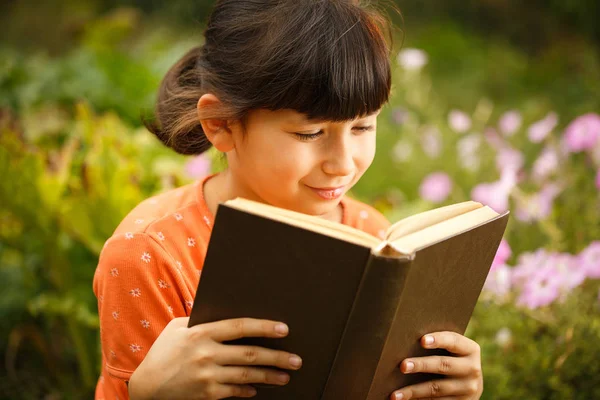Cute girl is reading outdoors on an sunny day, international literacy day.