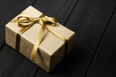 Siyah ahşap arka plan üst görünümünde kurdele ile hediye kutusu.
