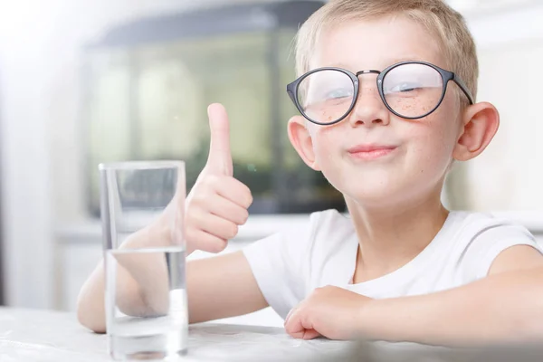 Kleine jongen in de keuken met een glas schoon water — Stockfoto