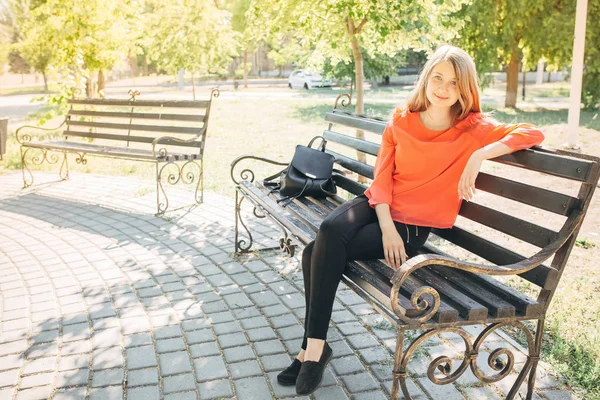 Menina bonita com mochila sentada em um banco — Fotografia de Stock