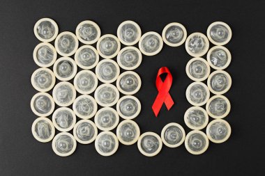 Siyah arka planda prezervatifli AIDS kurdelesi