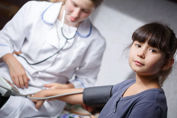 female doctor in white coat measures pressure on a child