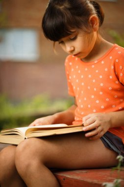 Sevimli kız güneşli bir günde açık havada okuyor, uluslararası okuryazarlık günü.