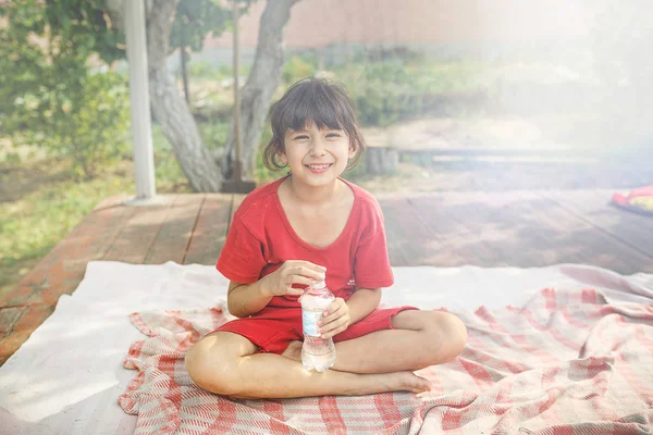 Kleines Mädchen mit Wasserflasche auf der Terrasse an sonnigen Tagen. — Stockfoto